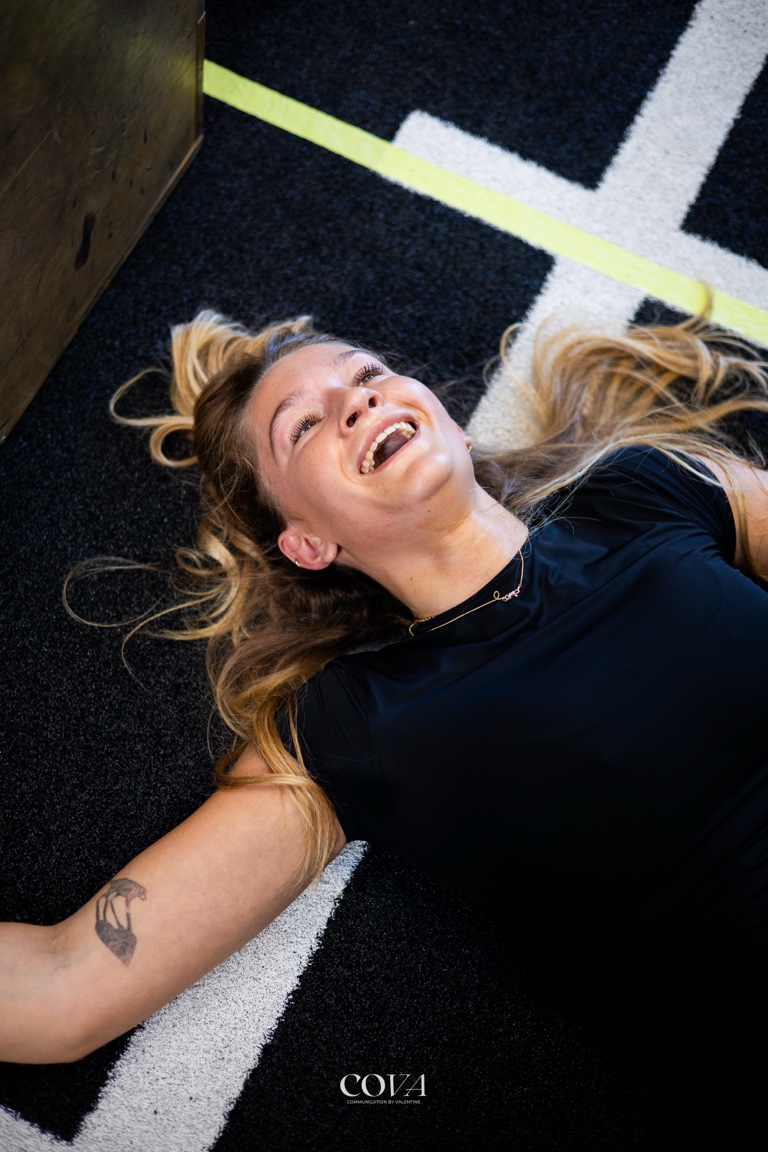 Une adhérente allongée au sol, hilare, à la fin d’un WOD.